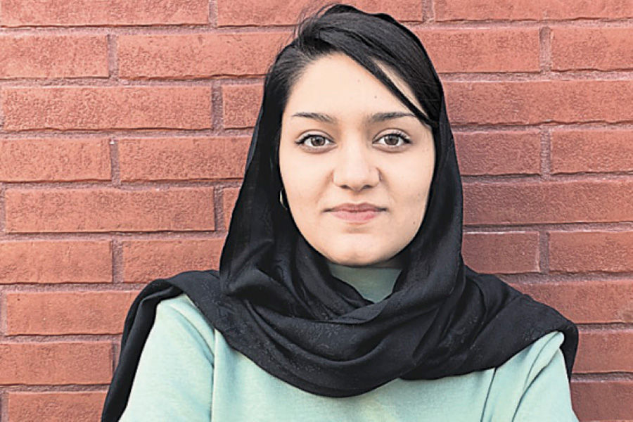 Bard College Berlin stduent Aisha Khurram, standing with arms crossed looking at the camera and smiling with determination.; Read More on unhcr.org