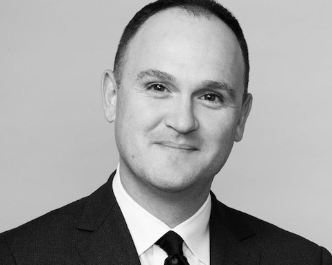 Image of Max Kenner &rsquo;01, executive director of the Bard Prison Initiative, sitting on a couch in a suit and tie, facing the camera.; Read More in the&nbsp;New York Times