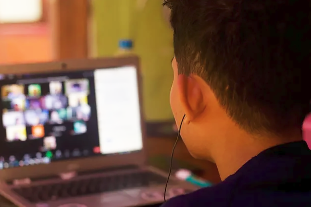 Students sitting at a roundtable with a professor using computers.