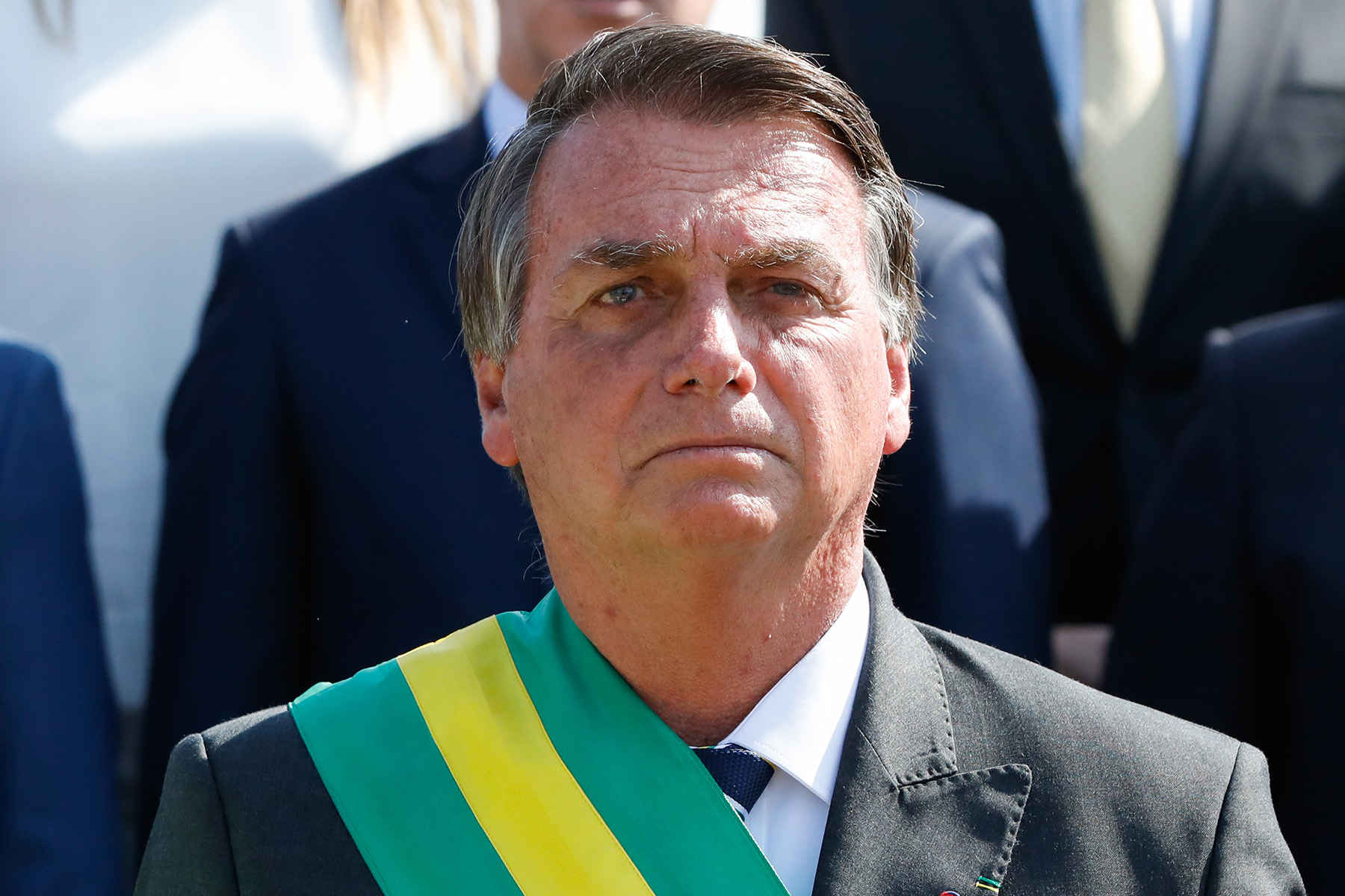 Jair Bolsonaro wearing a green sash looking ahead pensively.; Listen Now on NPR