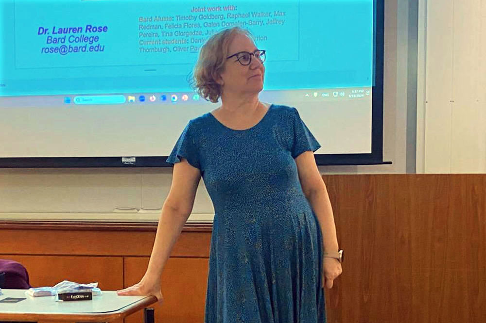 Associate Professor of Mathematics Lauren Rose. A woman in a blue dress stands in front of a screen.; Watch on the Today Show