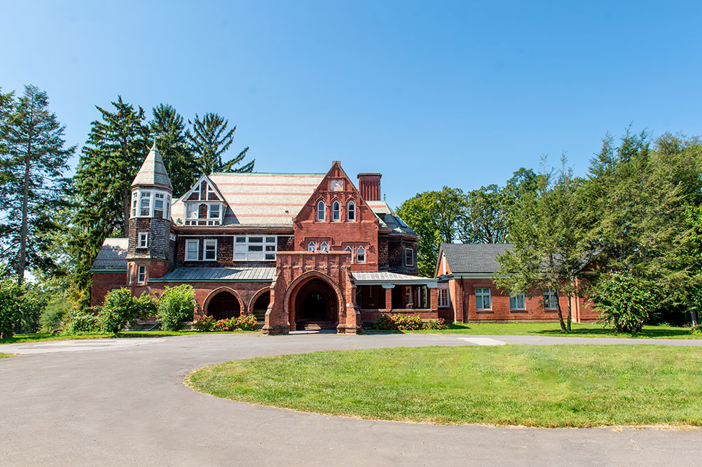 A brick mansion in the middle of a lush green field