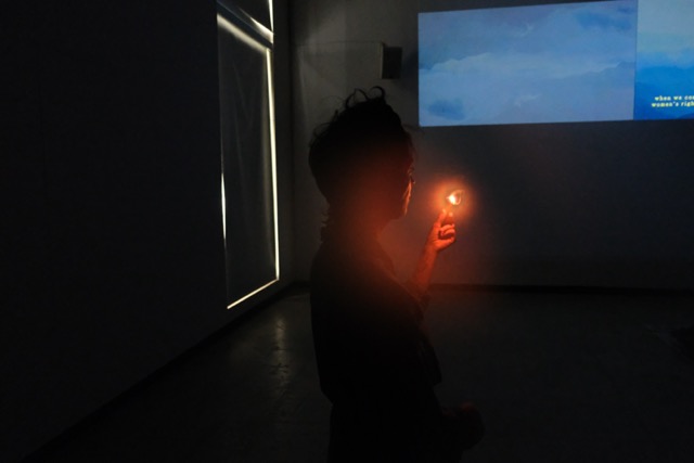 Carol Monteleagre holding up a small flame to a projected image