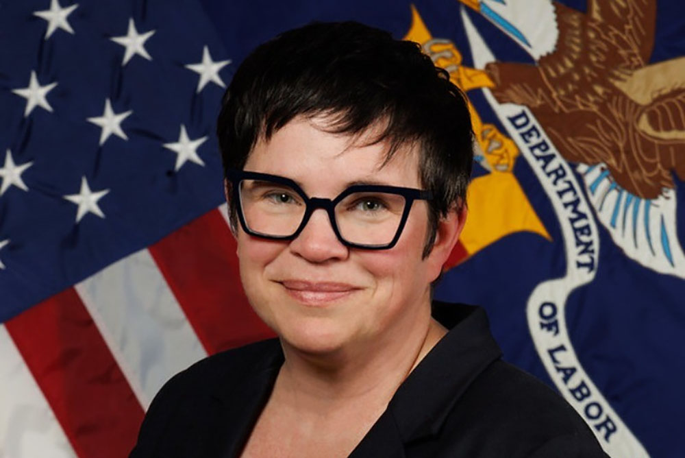 Close up portrait in front of American flag and Department of Labor flag.