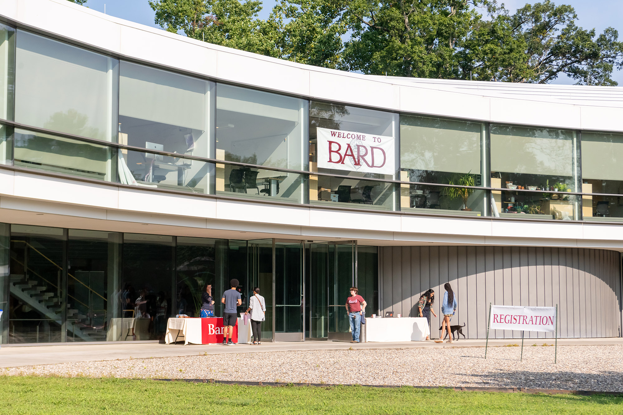 Students stand outside an academic building in the sunlight