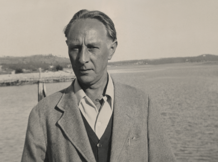 a black and white photo of a man in front of a marina with the ocean in the background