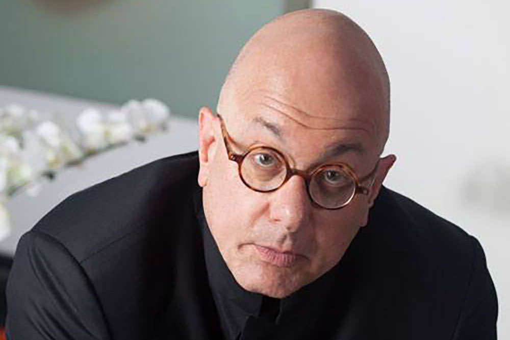 A man in a black shirt looks at the camera.