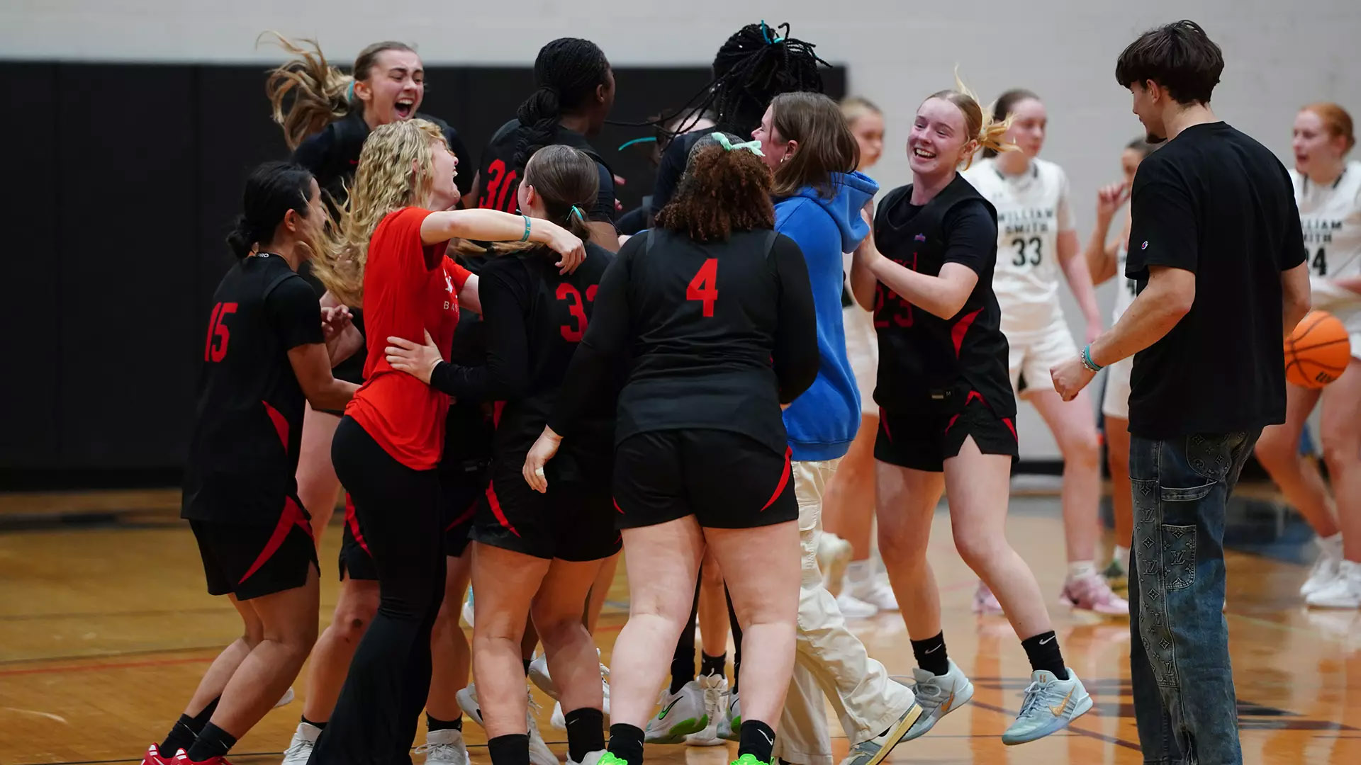 a group of basketball students hug on the court after their victory