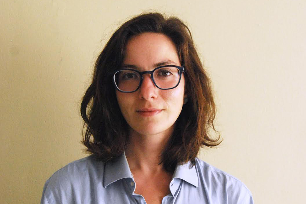 a woman in glasses and a blue shirt looks at the viewer