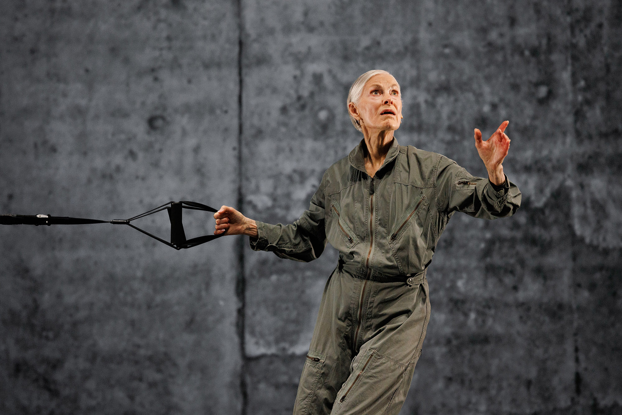 a woman in a green jumpsuit holds a rope handle