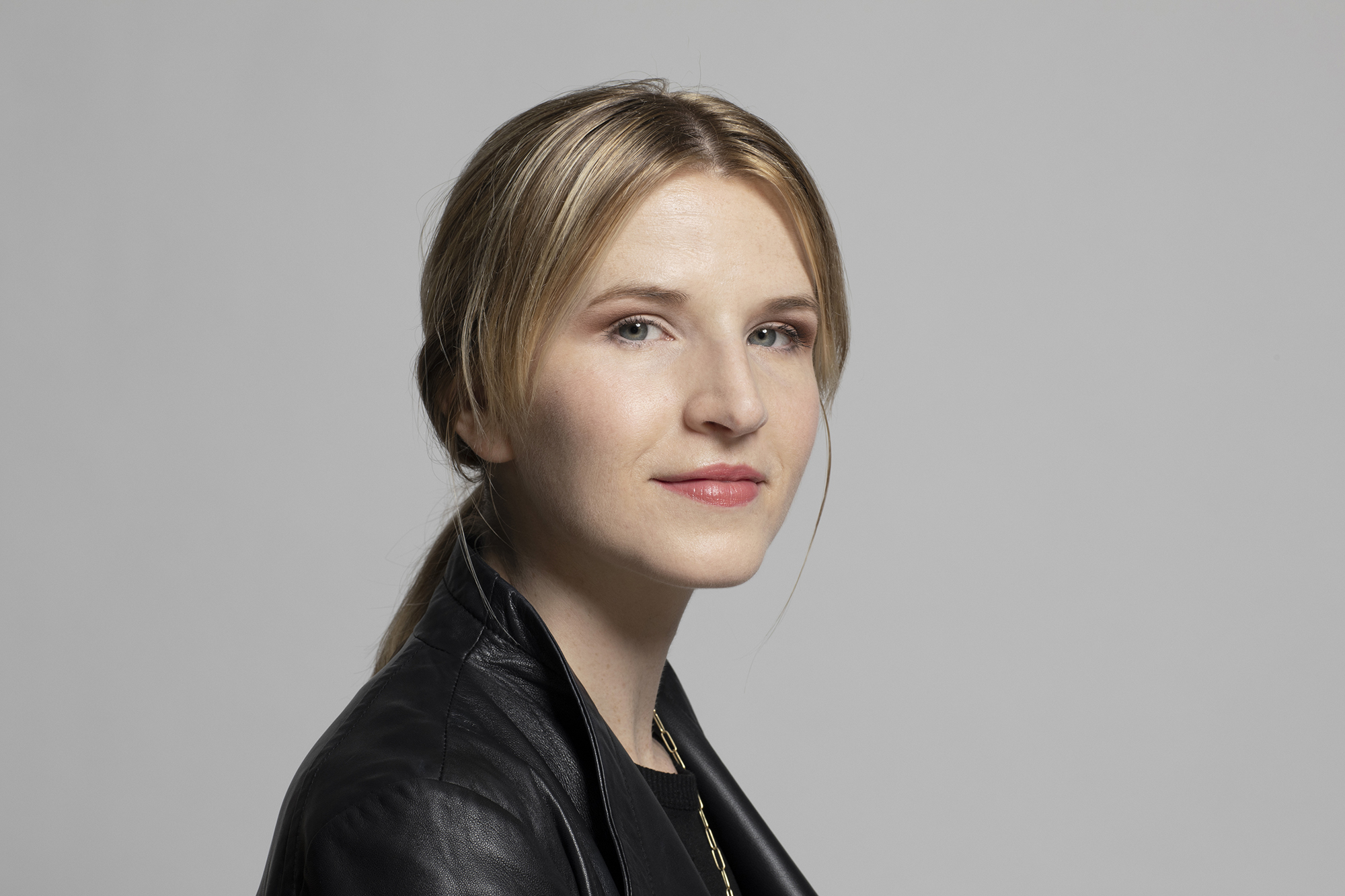 a woman with blonde hair in a black jacket smiles at the viewer