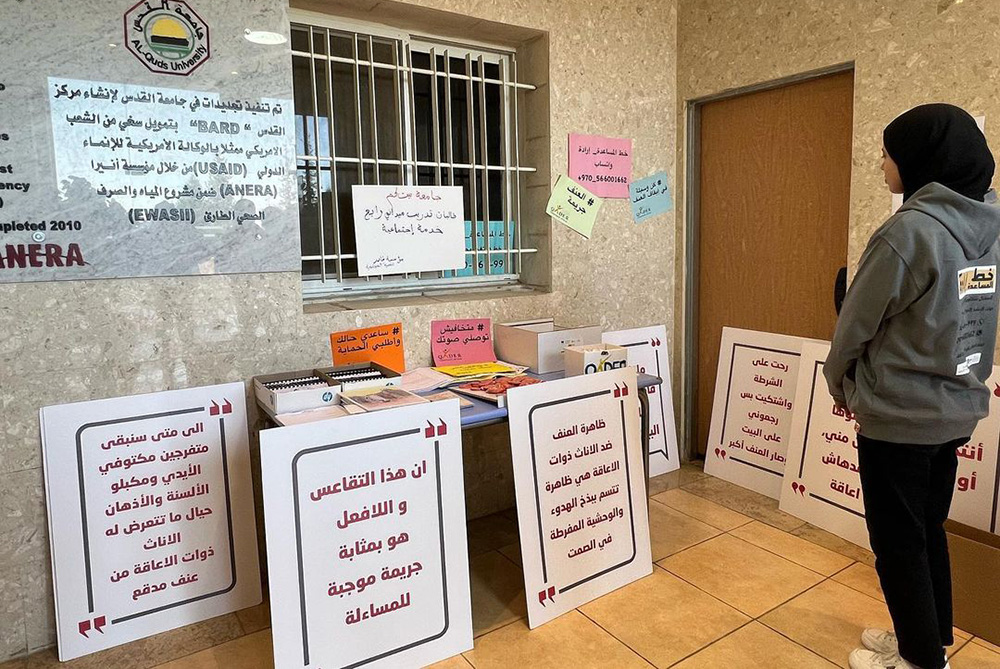 An AQB student examines signage from Qader, an organization that works with women and girls with disabilities. One slogan reads &quot;Violence against females with disabilities is often characterized by the phenomenon of calm and silence in the face of excessive brutality.&quot; Photo by Womenity.