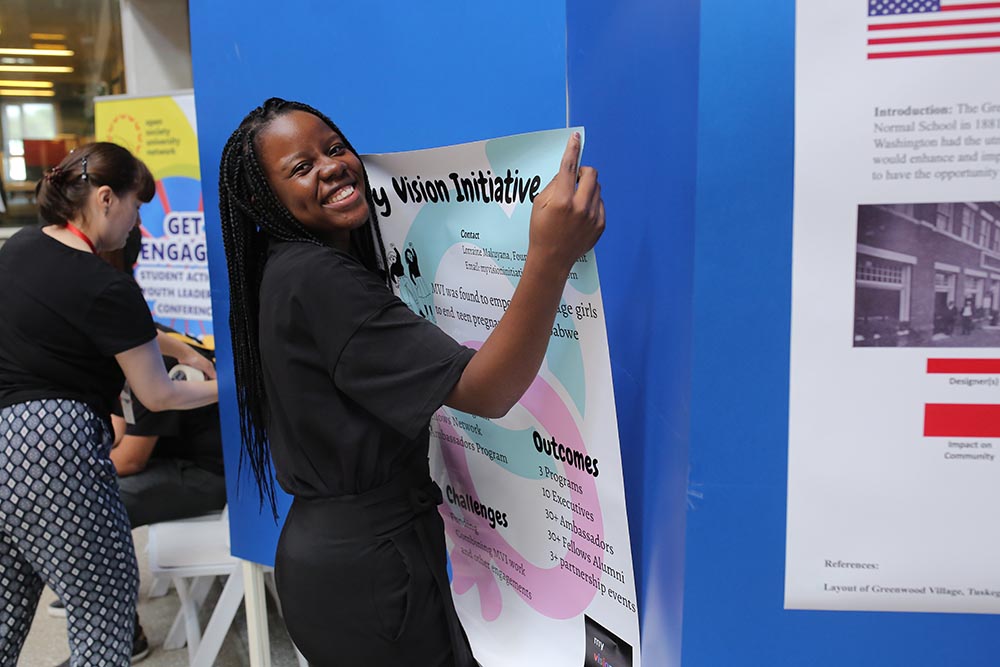 Lorraine Makuyana, Global Engagement Fellow at&nbsp;Ashesi University, prepares a poster describing her project for a networking session. Photo courtesy of AUCA.